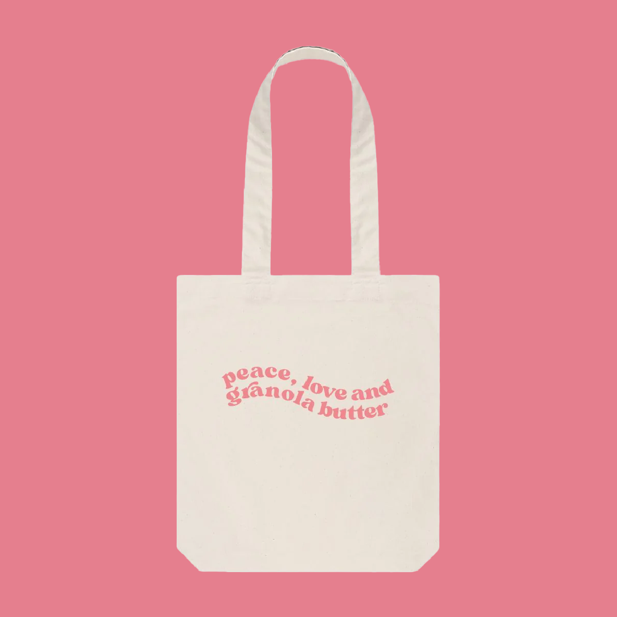 A cream tote bag with pink swirly font placed in the centre of the bag, our Granola butter merchandise